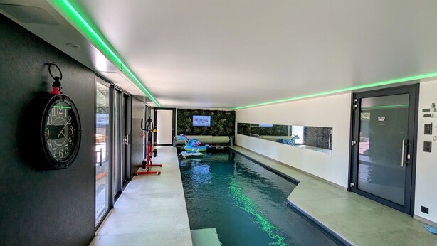 A modern indoor swimming pool with a clear water path, a clock on the wall, and a door labeled 'ACCESS PRIVÉ'. - Family Retreat with Terrace and Pool Access (Jeanménil)