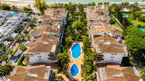 Een resort met meerdere gebouwen, een centraal gelegen zwembad en uitzicht op het strand.