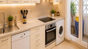 Een moderne keuken met een vaatwasser, oven, wasmachine, een spoelbak en een raam met uitzicht.
