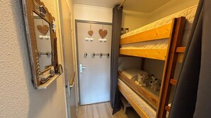 Ein schmales Gang mit einem Bunkelbett rechts, einer Tür mit herzförmigen Verzierungen und einem Spiegel links.