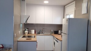 A compact kitchen with white cabinets, a sink, a microwave, a kettle, and a refrigerator. - Beautiful 2-bed apt with sea view, glassed-in terrace, parking, 750m from the beach in Roses (Roses)
