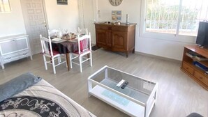 A living room with a dining table, chairs, a glass coffee table, a TV stand, and a window with a view. - Beautiful 2-bed apt with sea view, glassed-in terrace, parking, 750m from the beach in Roses (Roses)