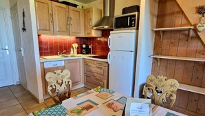 A compact kitchen with wooden cabinets, a microwave, and a refrigerator. - Duplex with south-facing balcony - 5 guests (Saint-Michel-de-Chaillol)