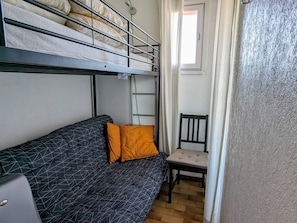 Et sovesal med køjesenge, en sofa, en stol og et vindue.