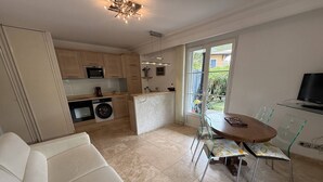 A modern kitchen with a dining area, a washing machine, and a TV. - Charming apartment, air conditioning - 2 guests (La Croix-Valmer)