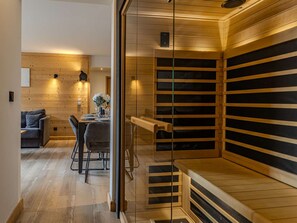 A sauna with wooden slats, a glass door, and a wooden bench. - Luxury apartment, parking, 6 guests - Belle Plagne (Belle Plagne)