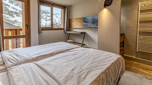 A bedroom with two beds, a wooden desk, a mounted TV, and a wall-mounted towel rack. - Luxury apartment, parking, 6 guests - Belle Plagne (Belle Plagne)