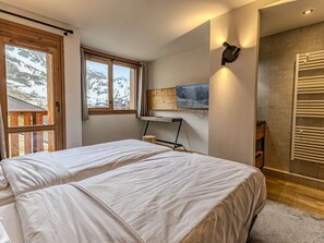 A bedroom with two beds, a wooden desk, a mounted TV, and a wall-mounted towel rack. - Luxury apartment, parking, 6 guests - Belle Plagne (Belle Plagne)