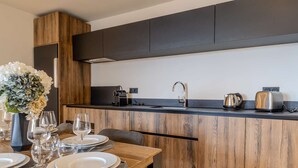 A modern kitchen with wooden cabinetry, a black countertop, and a dining area set with plates, glasses, and a vase of flowers. - Luxury apartment, parking, 6 guests - Belle Plagne (Belle Plagne)
