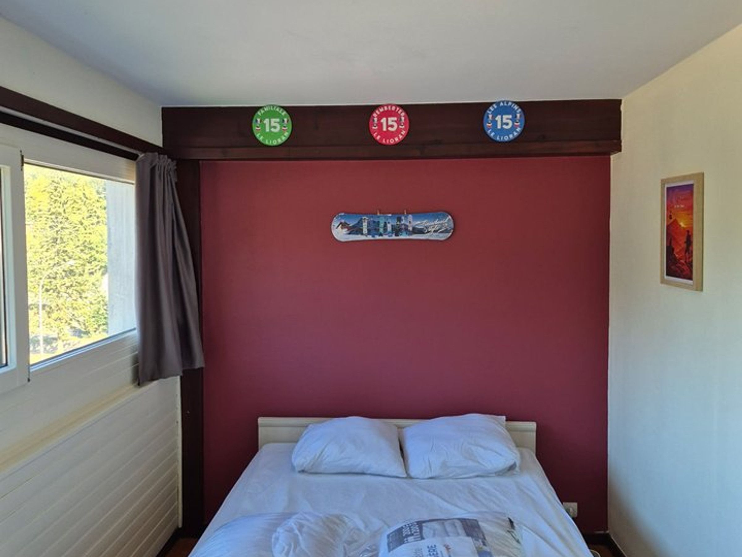 A bedroom with a bed, a window with curtains, and three circular signs on the wall.