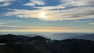 A mountainous landscape with a clear sky and the sun setting or rising.