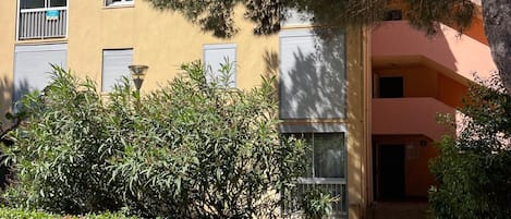 A building with multiple windows, a pathway, and surrounding greenery.