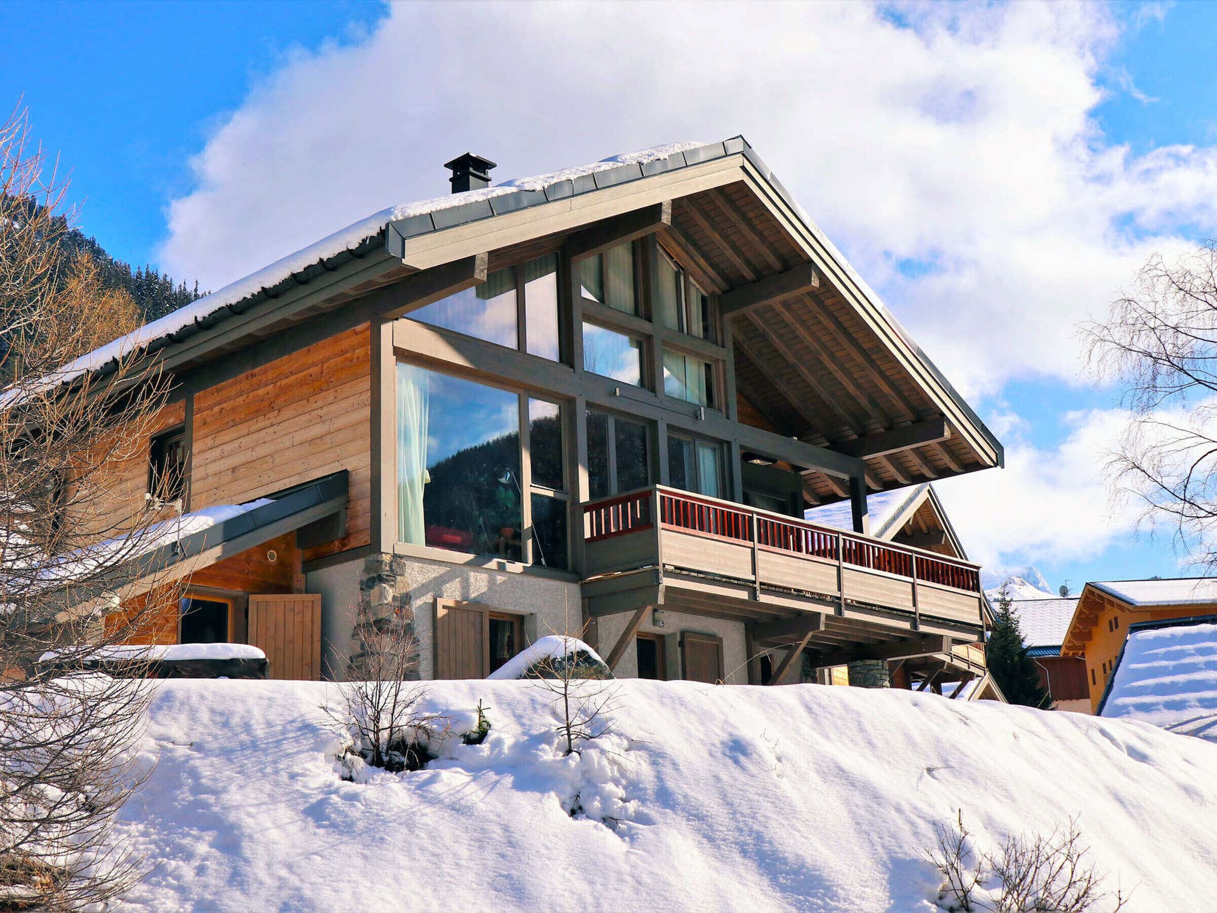 Un moderno chalet con facciata in legno, ampie finestre e un balcone.