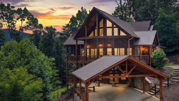 Ein großes, mehrstöckiges Holzhaus mit umlaufender Veranda, großen Fenstern und einem Steinfundament.