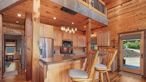Ein Holzinterieur mit Küchenzeile, hölzernen Barhocker und Blick durch eine Tür.