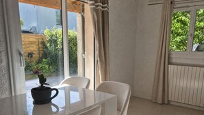 A modern dining area with a glass table, two chairs, a potted plant, and a view of greenery outside. - *Ma bulle* private house (La Cadière-d'Azur)