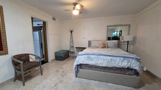 A bedroom with a bed, a chair, a floor lamp, and a ceiling fan. - Ahoy kids! Pirate's Grotto Apartment by Airport and Stadium (Tampa)