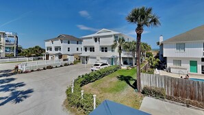 A residential area with houses, a swimming pool, and a palm tree. - 50 Steps to the Beach | Spacious, Gas Grill, Beach Access (Tybee Island)