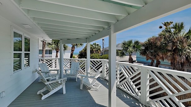 A covered deck with white railings, white rocking chairs, and a view of the ocean. - 50 Steps to the Beach | Spacious, Gas Grill, Beach Access (Tybee Island)