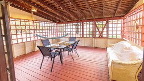 A covered patio with a table and chairs, a wicker sofa, and a hammock. - Charming 2-bedroom Apartment with AC at gorgeous Crane Beach (Bridgetown)