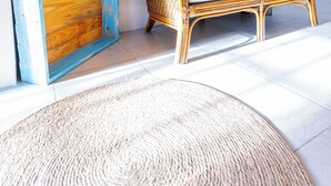 A room with a wicker sofa, a blue-painted wooden shelf, and a woven rug. - Charming 2-bedroom Apartment with AC at gorgeous Crane Beach (Bridgetown)
