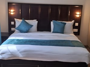 A neatly made bed with a dark headboard, two pillows, and a blue accent pillow. - Riata Loltome (Nyahururu)