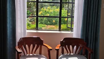 Duas cadeiras de madeira viradas para uma janela com vista para um jardim.