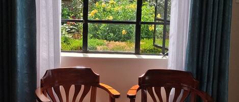 Two wooden chairs facing a window with a view of a garden.