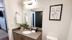 Een moderne badkamer met een houten wastafelmeubel, twee wastafels, een grote spiegel en een toilet.