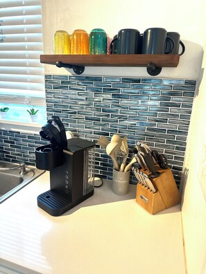 A kitchen with a coffee maker, utensils, and a shelf with colorful mugs. - House in Panama City Beach ~ Mermaid Oasis (Panama City)