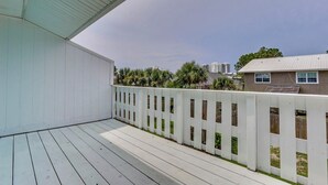 Een overdekt terras met een witte balustrade, uitzicht op een woonwijk, en een heldere lucht.