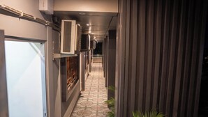 A hallway with air conditioning units, a patterned floor, and a door on the left.