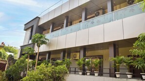 A modern building with multiple floors, large windows, and air conditioning units.