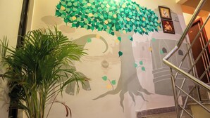 A staircase with a tree mural on the wall, a potted plant, and a framed picture.