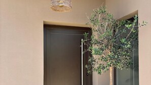 A modern building entrance with a dark door, a hanging light fixture, and a potted tree. - Vila d'Arrabida (Quinta do Anjo)