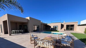 A modern outdoor patio with a pool, outdoor furniture, and a covered seating area. - Vila d'Arrabida (Quinta do Anjo)