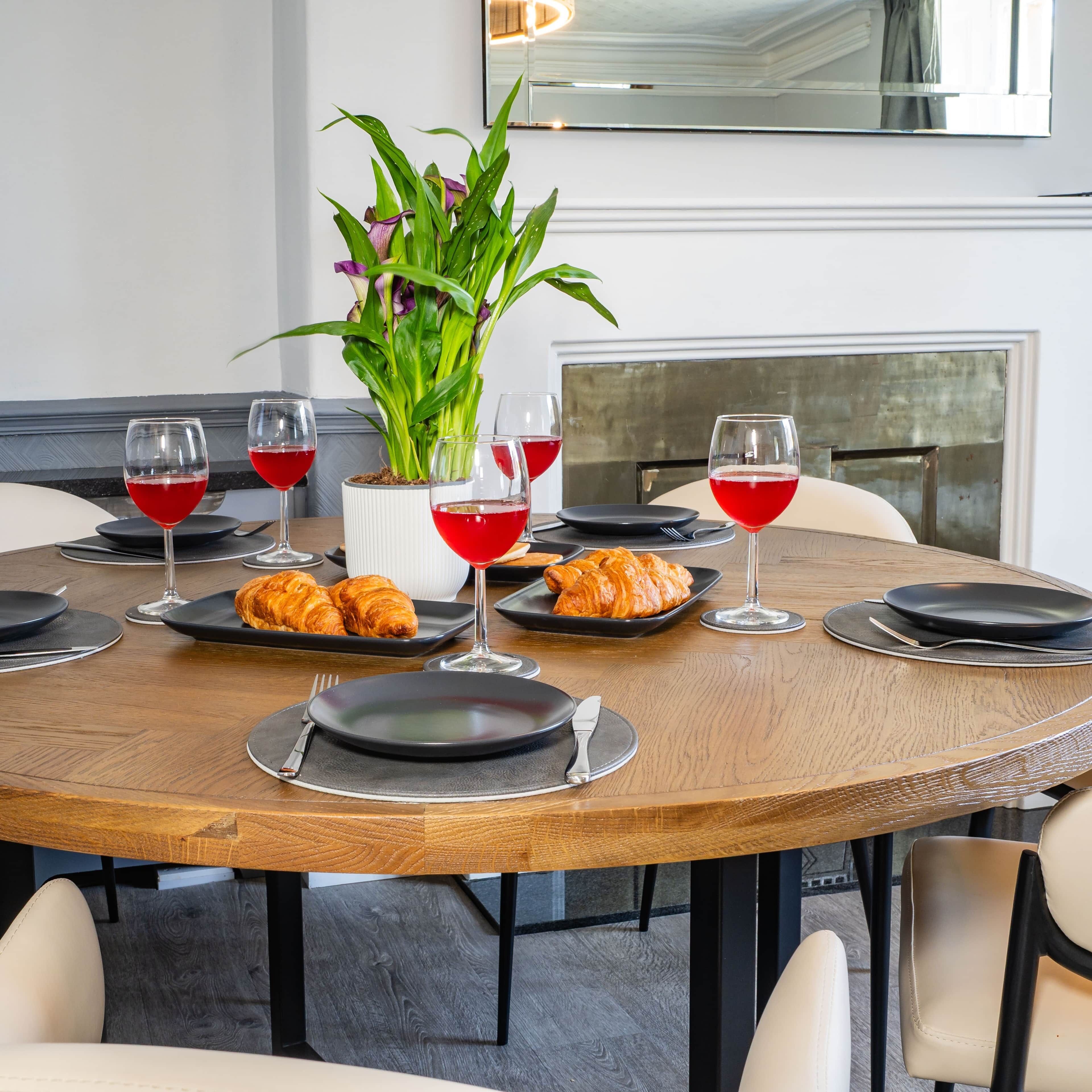 A round dining table with plates, croissants, and wine glasses.