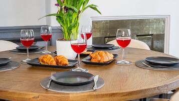 A round dining table with plates, croissants, and wine glasses.