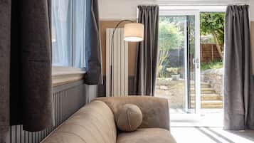 A living room with a sofa, a lamp, and a view of a garden through a glass door.