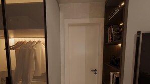 Ein begehbarer Kleiderschrank mit Kleiderstange, einer Tür zu einem Raum und einem Bücherregal mit Büchern und Dekoration.