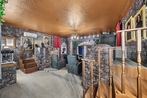 A room with stone walls, a chandelier, a staircase, and framed pictures on the wall. - 9BR villa sleeps 22 with pool table in kissimmee (Kissimmee)
