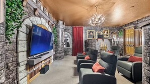 A stone-walled room with a flat-screen TV, a chandelier, and a fireplace. - 9BR villa sleeps 22 with pool table in kissimmee (Kissimmee)