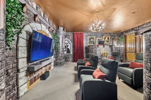 A stone-walled room with a flat-screen TV, a chandelier, and a fireplace. - 9BR villa sleeps 22 with pool table in kissimmee (Kissimmee)