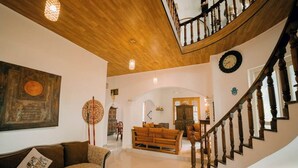 Amplia sala de estar con escalera de madera, un sofá y una mesa de comedor.