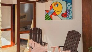 Una habitación con dos sillas de madera, un cuadro abstracto colorido y una lámpara de fibra.