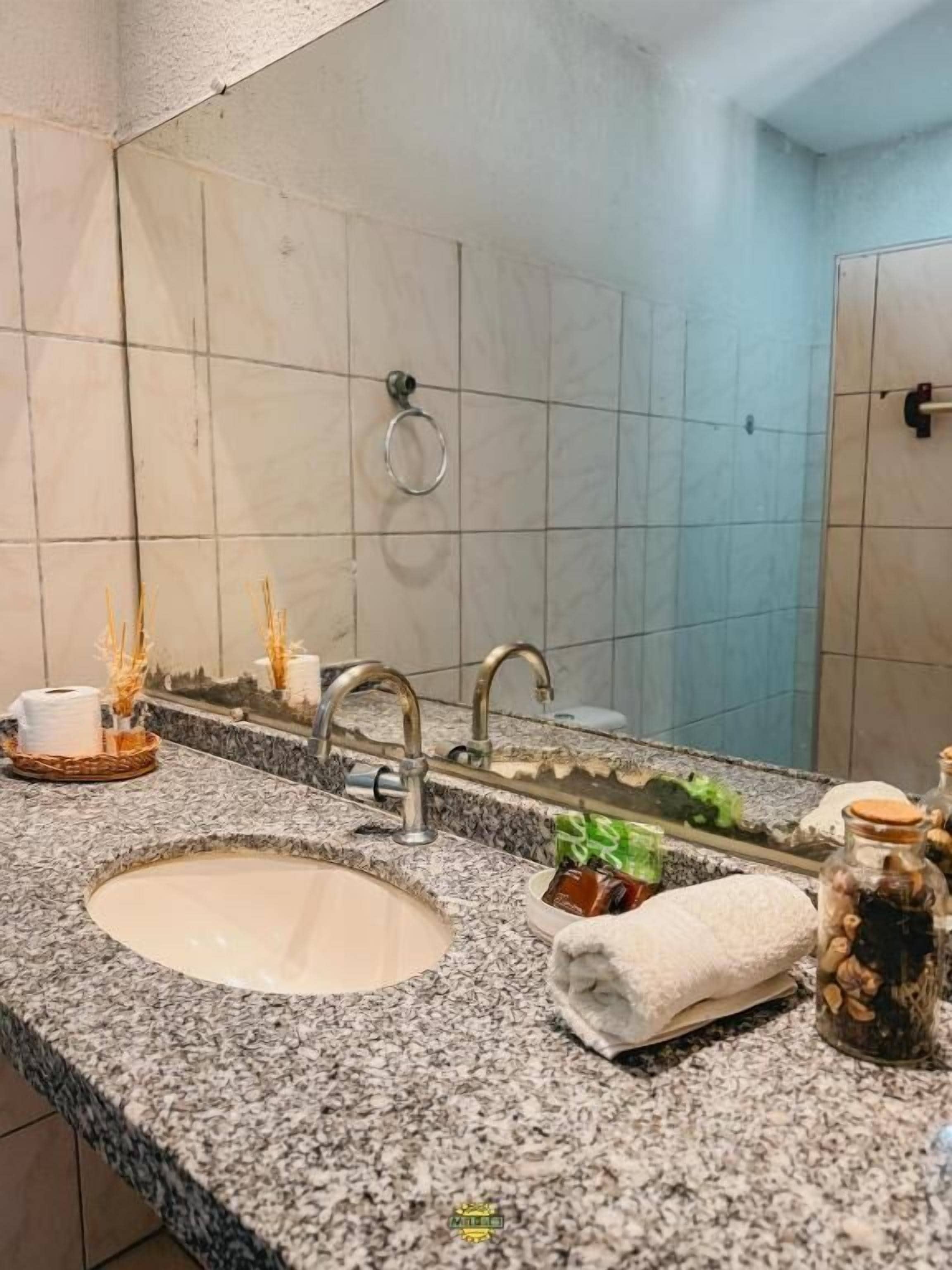 Ein Badezimmer mit Granitplatte, einem Waschbecken, einem Spiegel und einem Handtuchhalter.