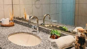 Ein Badezimmer mit Granitplatte, einem Waschbecken, einem Spiegel und einem Handtuchhalter.