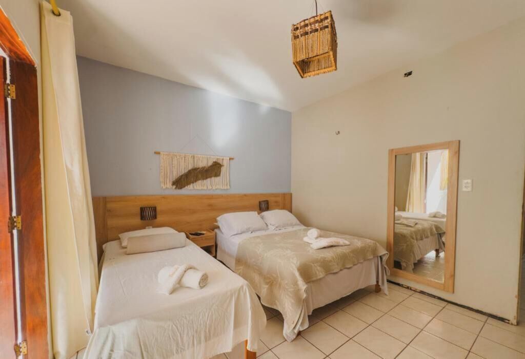 A hotel room with two beds, a wooden headboard, a mirror, and a hanging light fixture.