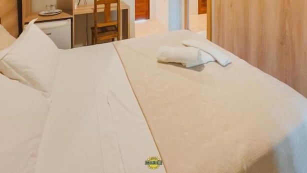 Habitación de hotel con cama, escritorio, silla, televisor montado en la pared y aire acondicionado.