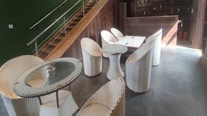 Een modern interieur met een trap, rieten meubels, een barhoek en een groene wand.